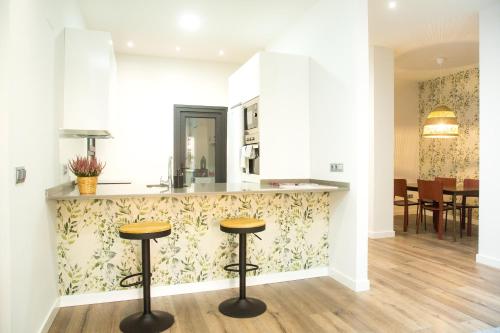 a kitchen with two stools in front of a counter at Elegante Apartamento LAUD1 - Nuevo/Familia/Wifi/TV in Valladolid