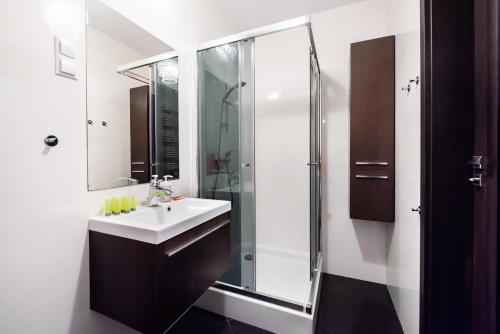 a bathroom with a sink and a shower at Wola Pleasure Place Apartment in Warsaw