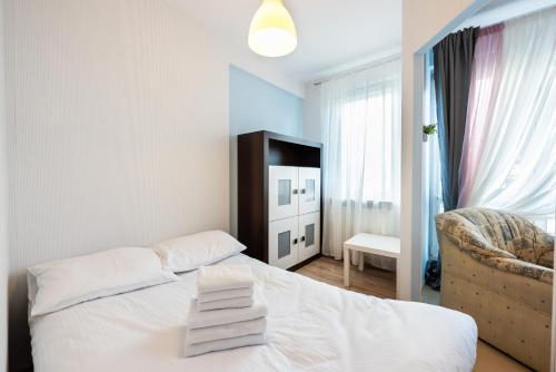 a bedroom with a white bed and a chair at Wola Pleasure Place Apartment in Warsaw