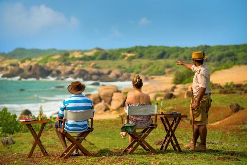 a group of people sitting at a table looking at the ocean at Uga Chena Huts - Yala - All Inclusive in Yala