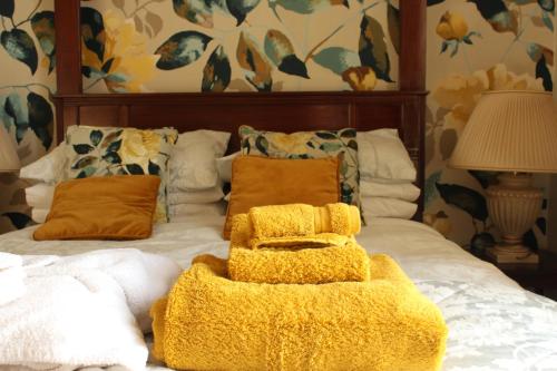 a bed with a yellow blanket and pillows on it at Bank House B and B in Penrith