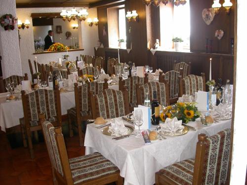 d'une salle à manger avec des tables et des chaises blanches ornées de fleurs. dans l'établissement Hotel Miravalle, à Imer