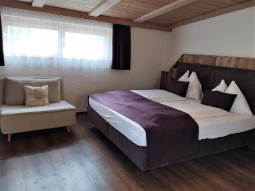 - une chambre avec un grand lit et une chaise dans l'établissement Bergidyll 12 by Alpenidyll Apartments, à Ramsau am Dachstein