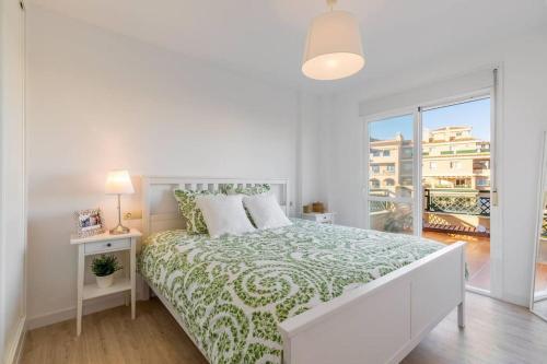 a white bedroom with a bed and a large window at Apartamento Calma Beach Home in Torremolinos