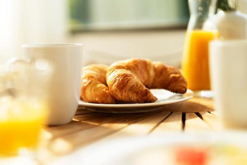 a plate of croissants and orange juice on a table at Haus4Zimmer - Luxus mit Blick über den Bodensee - mit Garage in Bregenz