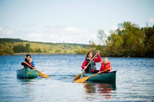 a woman and two children in kayaks on a lake at Flott fritidsleilighet i Bualie på Golsfjellet in Gol