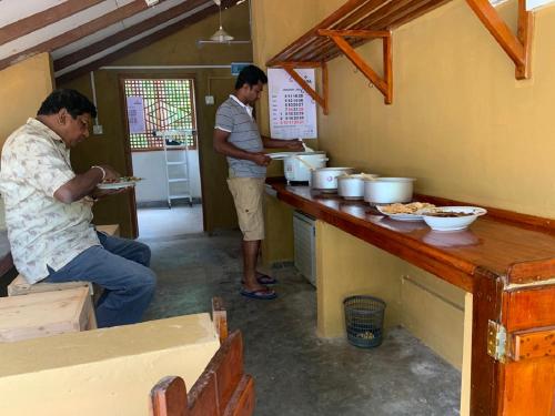 two men standing in a kitchen preparing food at Captain's Cottage at Yala in Kataragama