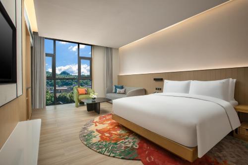 a bedroom with a large white bed and a living room at Holiday Inn Resort Guiyang Qingyan, an IHG Hotel in Guiyang