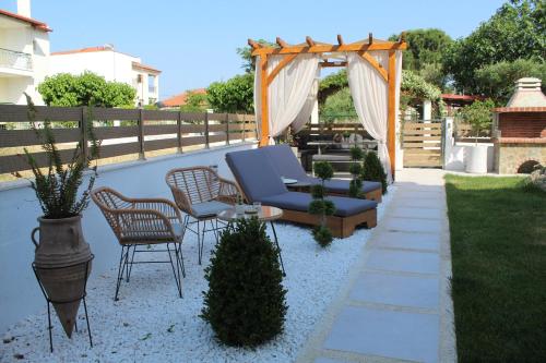 un patio con un sofá azul y sillas en un patio trasero en Azure Bliss Suites, en Nikiti