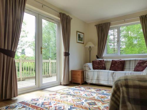 a living room with a couch and large windows at Bo Nan Taigh Cottage in Aberfoyle