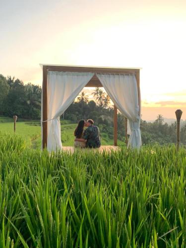een stel zit op een deken onder een prieel bij Bali De Pardis Cottage in Munduk
