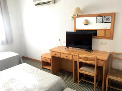 Habitación con escritorio, TV y cama. en HOSTAL LA POSADA en Espirdo