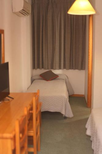 EspirdoにあるHOSTAL LA POSADAのベッド、デスク、窓が備わる小さな客室です。