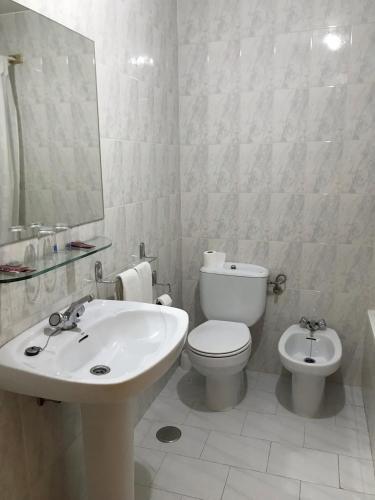 Baño blanco con aseo y lavamanos en HOSTAL LA POSADA en Espirdo