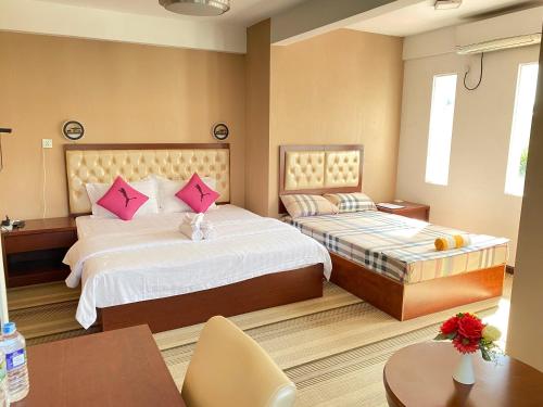 a hotel room with two beds with pink pillows at Sundale Hotel in Divulapitiya