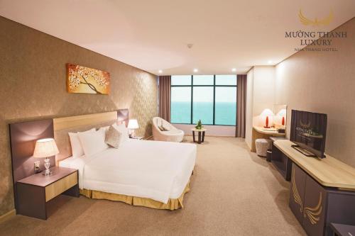 um quarto de hotel com uma grande cama branca e uma televisão em Muong Thanh Luxury Nha Trang Hotel em Nha Trang
