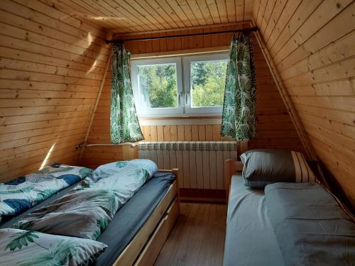 a room with two beds in a cabin with a window at Chata na Orave so saunou a kúpacou kaďou in Námestovo