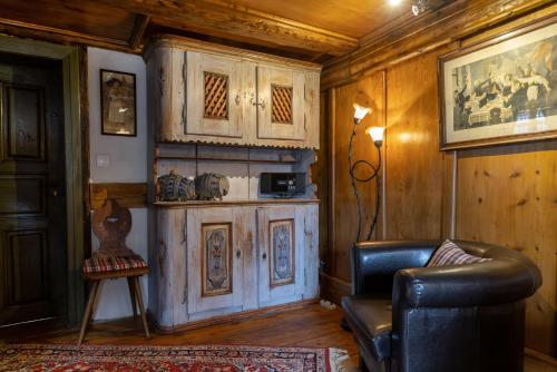 ein Wohnzimmer mit einem Ledersessel und Holzwänden in der Unterkunft ANNO 1698 Gîtes et Chambres d'Hôtes in Beblenheim