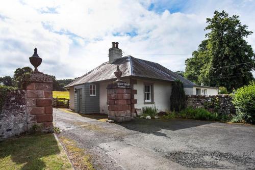 a small white house with a stone wall at Crailing West Lodge in Jedburgh