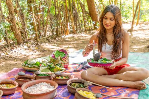 a woman sitting on a blanket with bowls of food at The Saraii Tree Lodge in Tissamaharama