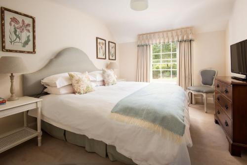 a bedroom with a large white bed and a window at Crailing Cottage in Jedburgh