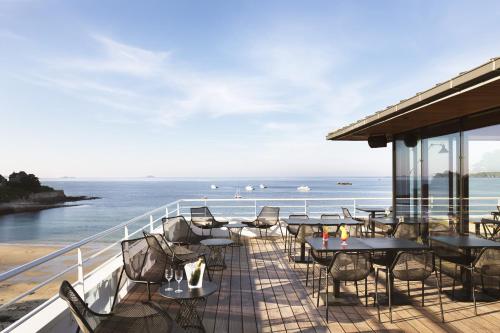 balcón con mesas y sillas y vistas al océano en Grand Hôtel Perros-Guirec en Perros-Guirec