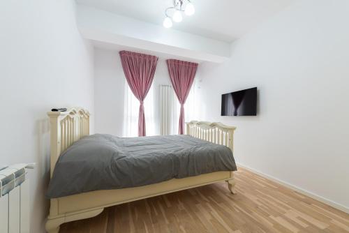 um quarto com uma cama com cortinas roxas e uma televisão em Ines em Bucareste
