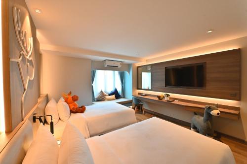 a hotel room with two beds and a flat screen tv at Moose Hotel Nimman in Chiang Mai