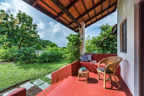 an outdoor patio with a red couch and chairs at SaffronStays Sattva - pet and eco-friendly villa in Mumbai's outskirts in Pen