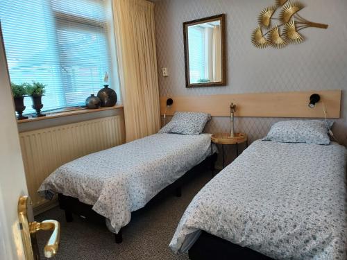 a bedroom with two beds and a mirror and a window at Familie Postma B&B Anjum in Anjum