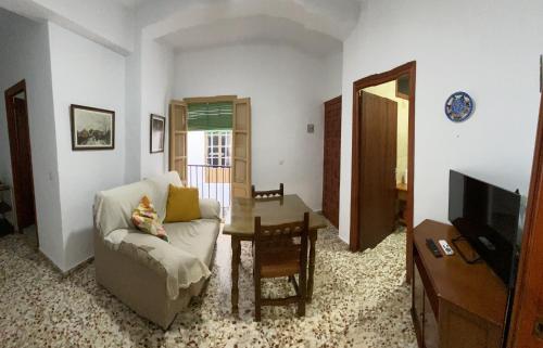 sala de estar con sofá, mesa y TV en Casa Pepe La Rosa, en Tolox