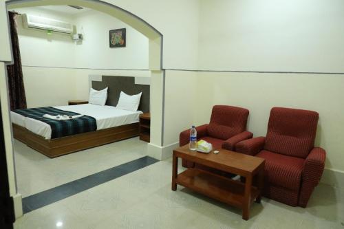 1 Schlafzimmer mit einem Bett, 2 Stühlen und einem Tisch in der Unterkunft Hotel Dream World Boarding & Lodging in Sivaganga