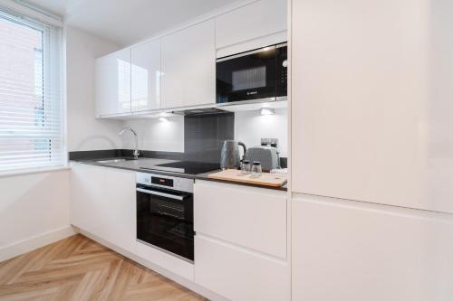 a white kitchen with white cabinets and a sink at Royal House Stylish Apartments - Chester in Chester