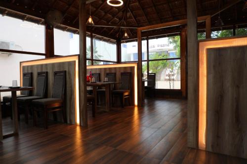 um restaurante com pisos e mesas de madeira e janelas em Hotel Dream World Boarding & Lodging em Sivaganga