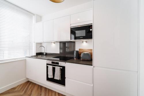 a kitchen with white cabinets and a black stove top oven at Royal House Stylish Apartments - Chester in Chester