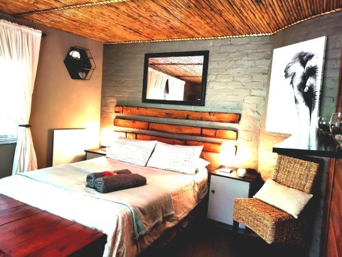 een slaapkamer met een bed, een spiegel en een stoel bij Cango Retreat Breathe in Oudtshoorn