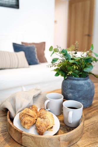 a table with a plate of pastries and cups of coffee at Royal House Stylish Apartments - Chester in Chester