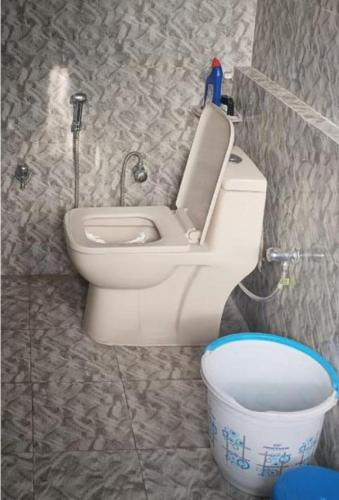 a bathroom with a toilet and a bucket at Anuppam Home Stay in Kulu