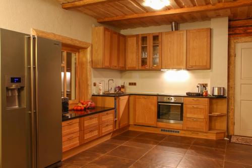 eine Küche mit Holzschränken und einem Kühlschrank aus Edelstahl in der Unterkunft Kalurikodu Holiday Home in Kärdla