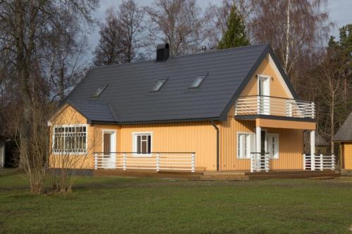 a yellow house with a black roof at Kalurikodu Holiday Home in Kärdla