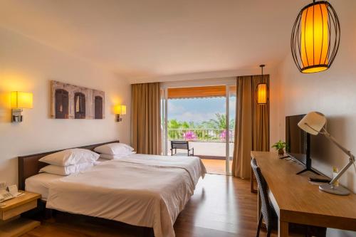 a hotel room with a bed and a desk and a window at Best Western Phuket Ocean Resort in Karon Beach