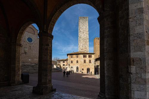 une arche dans un bâtiment avec une tour en arrière-plan dans l'établissement Torre Salvucci Maggiore Medieval Tower Experience, à San Gimignano