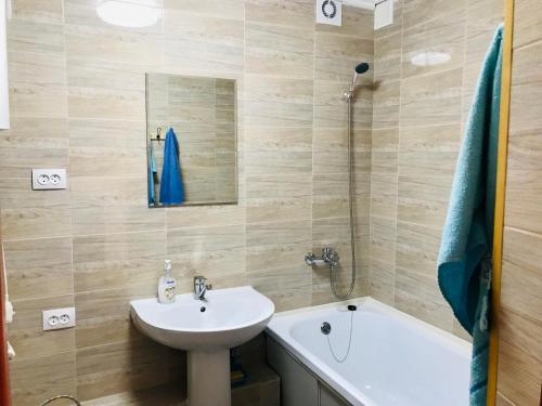 a bathroom with a sink and a mirror and a tub at Flat in the city center in Karagandy