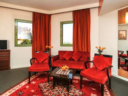 a living room with a red couch and two chairs at Ibis Marrakech Palmeraie in Marrakesh