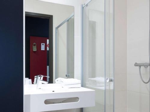 a bathroom with a sink and a shower with a mirror at ibis budget Oostende Airport in Ostend