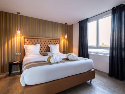 a bedroom with a large bed with a large window at Mercure Bale Mulhouse Aeroport in Blotzheim