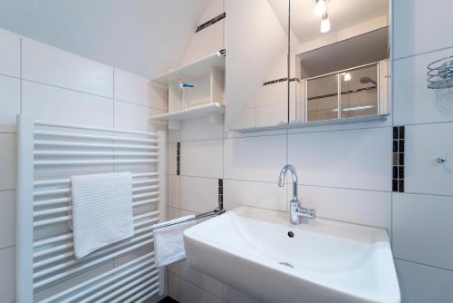 a white bathroom with a sink and a mirror at Badeweg 4 Strandläufer 2 in Scharbeutz