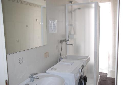 a white bathroom with a sink and a mirror at Appartamento "Rina Centro Sicilia" in Pietraperzia