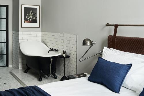 a bedroom with a sink and a bed and a bath tub at Gorgeous George by Design Hotels ™ in Cape Town