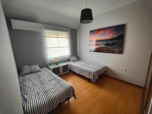 1 Schlafzimmer mit 2 Betten, einem Tisch und einem Gemälde in der Unterkunft GRAN ATICO en EL CENTRO CERCA DE LA PLAYA in Fuengirola
